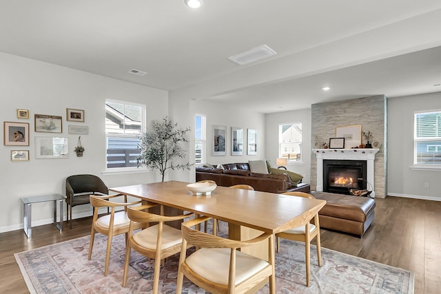 dining area featuring a fireplace, plenty of natural light, and hardwood / wood-style flooring