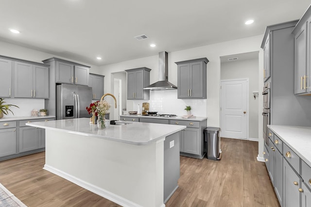 kitchen with gray cabinets, wall chimney range hood, and appliances with stainless steel finishes