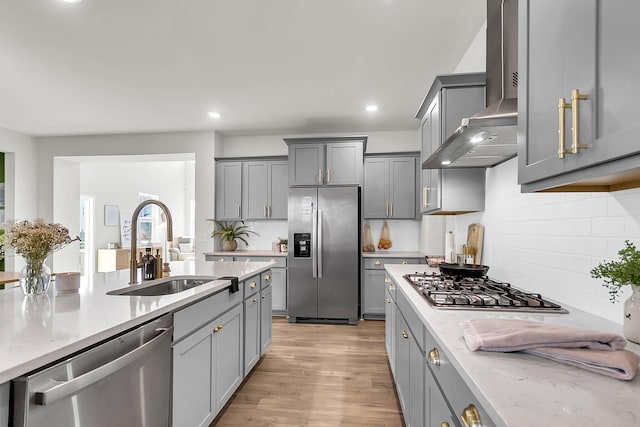 kitchen with appliances with stainless steel finishes, sink, gray cabinets, and wall chimney range hood