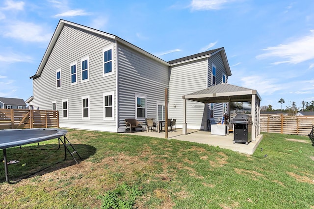 rear view of house with a yard, a trampoline, and a patio area