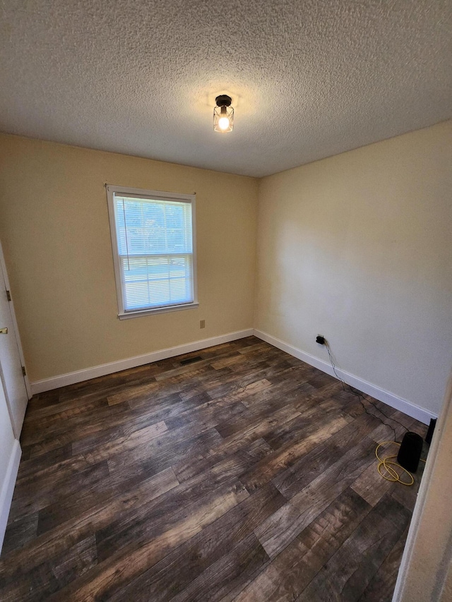 empty room featuring dark hardwood / wood-style flooring and a textured ceiling