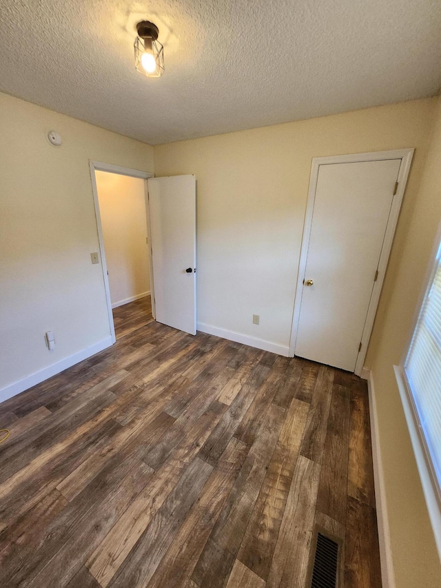 unfurnished bedroom featuring dark hardwood / wood-style flooring and a textured ceiling