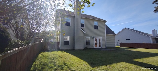 back of property with a lawn and french doors