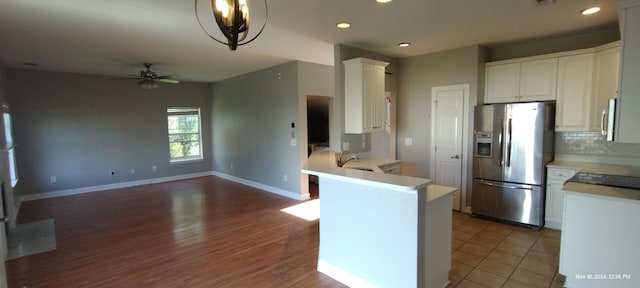 kitchen with sink, kitchen peninsula, hardwood / wood-style floors, white cabinets, and appliances with stainless steel finishes