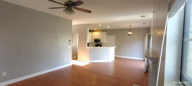 unfurnished living room featuring ceiling fan and dark hardwood / wood-style flooring