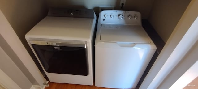 clothes washing area with light wood-type flooring and separate washer and dryer