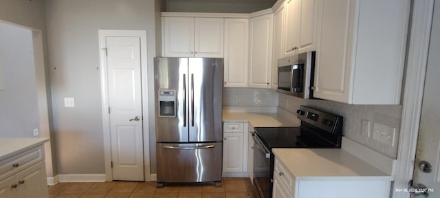 kitchen featuring tasteful backsplash, white cabinetry, light tile patterned flooring, and appliances with stainless steel finishes