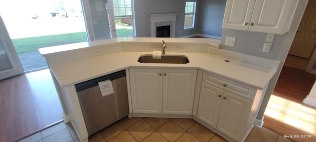 kitchen featuring stainless steel dishwasher, light tile patterned flooring, white cabinetry, and sink