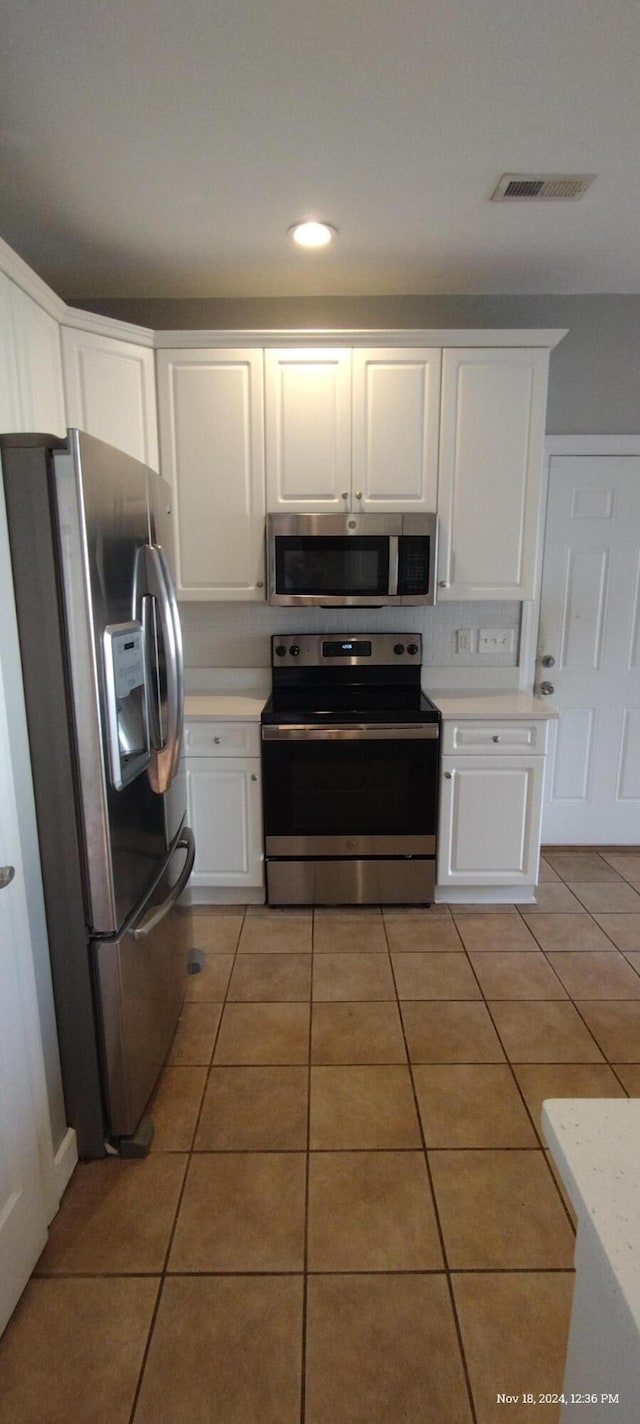 kitchen featuring light tile patterned floors, stainless steel appliances, and white cabinetry