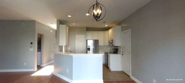 kitchen featuring an inviting chandelier, white cabinets, hanging light fixtures, hardwood / wood-style flooring, and appliances with stainless steel finishes