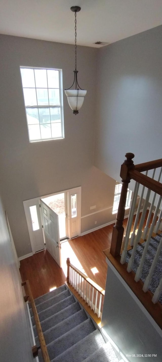 stairway with wood-type flooring and a high ceiling