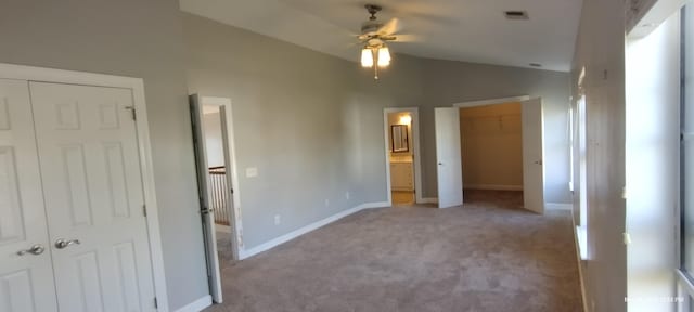 unfurnished bedroom featuring ensuite bathroom, ceiling fan, light colored carpet, and lofted ceiling