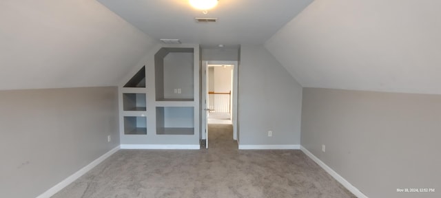 additional living space with light colored carpet and vaulted ceiling