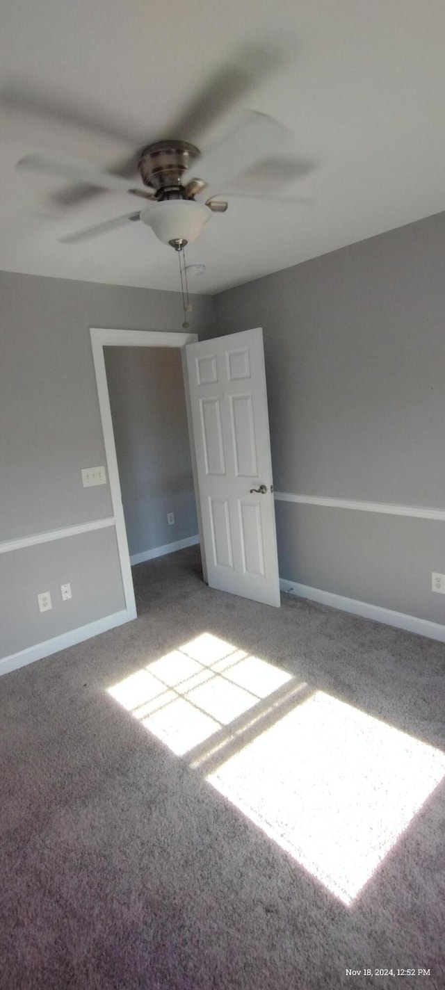 carpeted spare room with ceiling fan