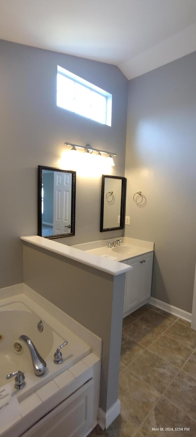 bathroom with tile patterned flooring, vanity, a bathtub, and lofted ceiling