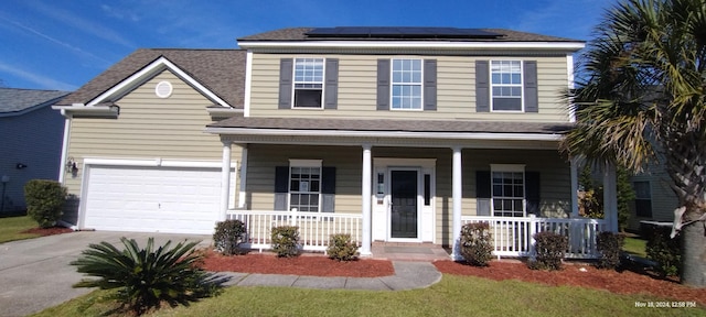 front facade featuring covered porch, solar panels, and a garage