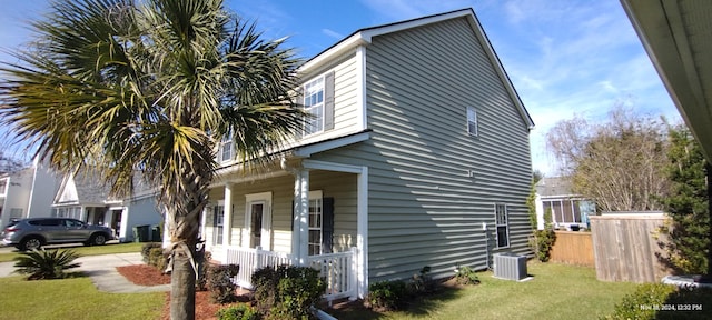 view of side of home with a yard, cooling unit, and a porch