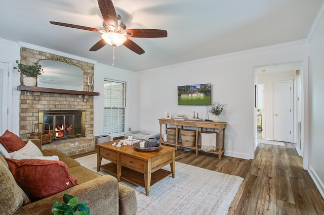 living room featuring crown molding, ceiling fan, hardwood / wood-style flooring, and a fireplace