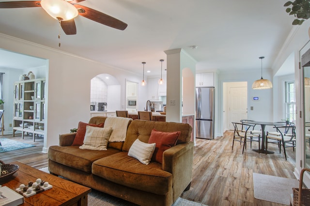 living room with ceiling fan, ornamental molding, sink, and light hardwood / wood-style flooring