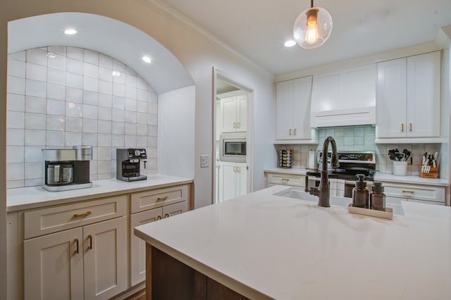 kitchen featuring pendant lighting, appliances with stainless steel finishes, backsplash, crown molding, and white cabinetry