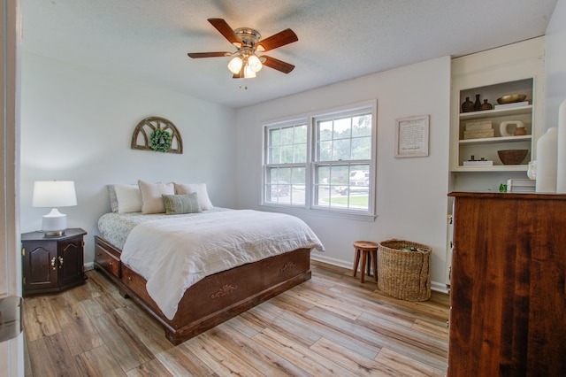 bedroom featuring a textured ceiling, ceiling fan, and light wood-type flooring