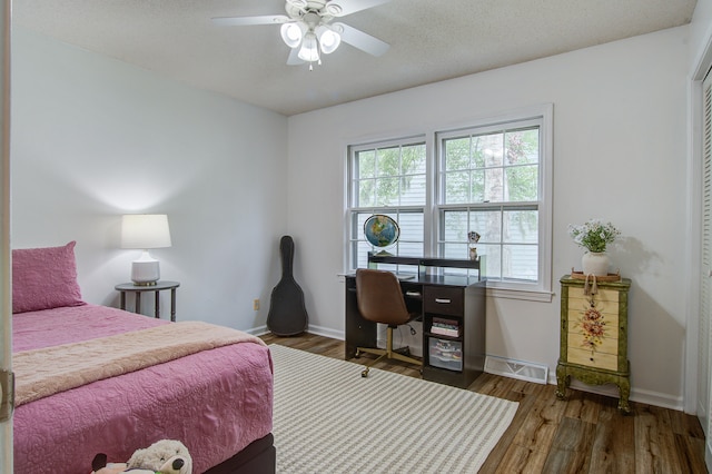 bedroom featuring dark wood-type flooring, a textured ceiling, and ceiling fan