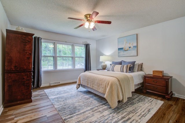 bedroom featuring a textured ceiling, ceiling fan, and wood-type flooring