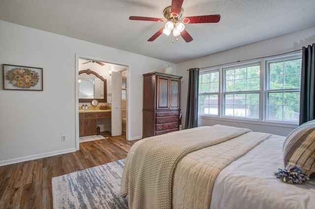 bedroom with a textured ceiling, wood-type flooring, ensuite bathroom, and ceiling fan