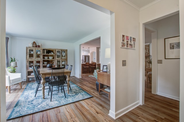 dining space with ornamental molding and hardwood / wood-style floors