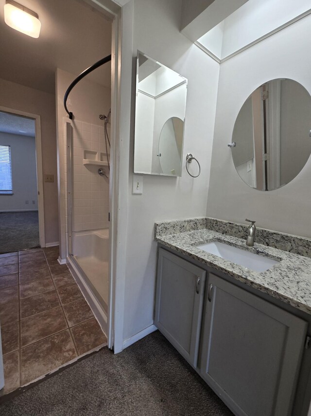 bathroom with tiled shower, tile patterned floors, and vanity