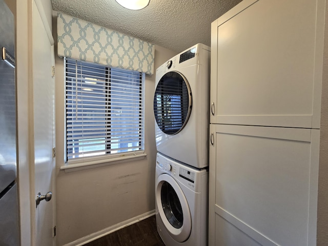 laundry room featuring stacked washing maching and dryer, a textured ceiling, dark wood-type flooring, and cabinets