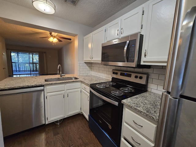 kitchen featuring sink, stainless steel appliances, tasteful backsplash, kitchen peninsula, and white cabinets