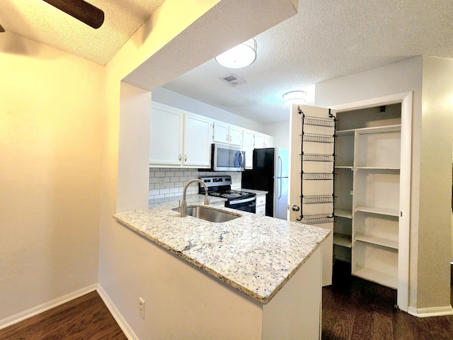 kitchen featuring appliances with stainless steel finishes, white cabinetry, decorative backsplash, sink, and kitchen peninsula