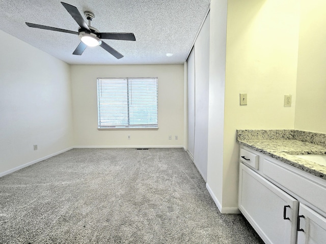 interior space featuring ceiling fan, light colored carpet, and a textured ceiling