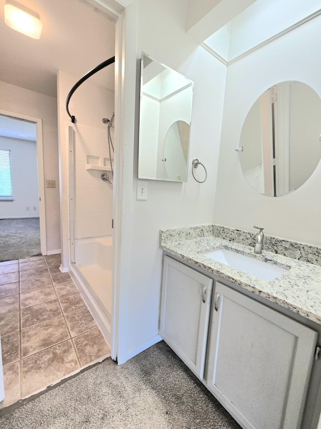 bathroom with a tile shower, tile patterned floors, and vanity