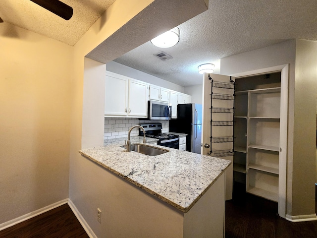 kitchen with white cabinets, stainless steel appliances, sink, backsplash, and kitchen peninsula