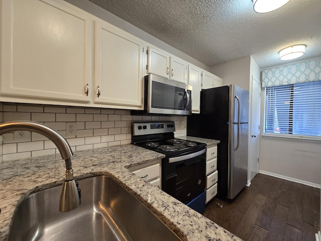 kitchen with sink, backsplash, white cabinetry, light stone counters, and stainless steel appliances