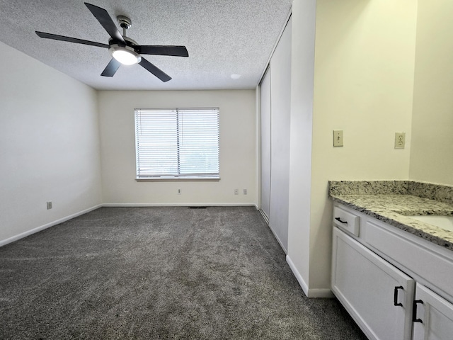 interior space with ceiling fan, dark colored carpet, and a textured ceiling