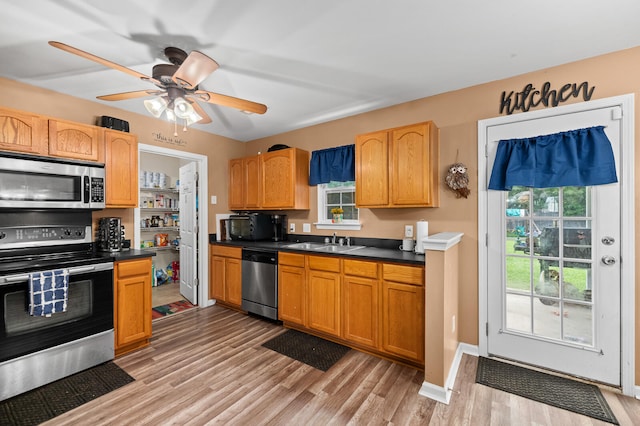 kitchen with stainless steel appliances, sink, light wood-type flooring, and ceiling fan