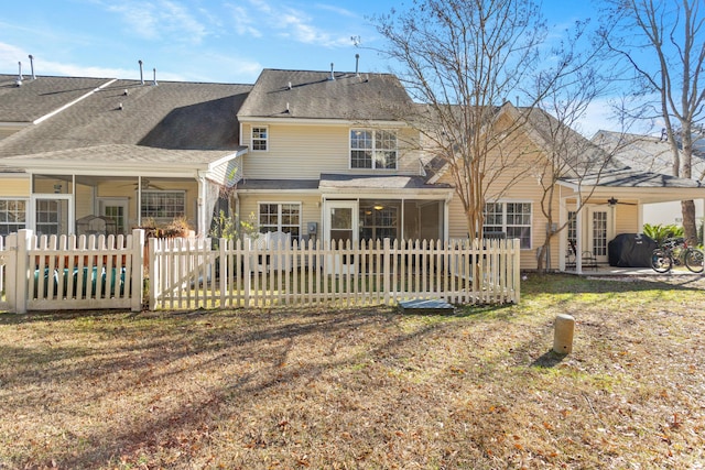 rear view of property with ceiling fan and a lawn