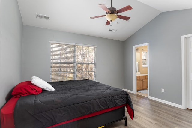 bedroom featuring wood-type flooring, ensuite bathroom, ceiling fan, and vaulted ceiling