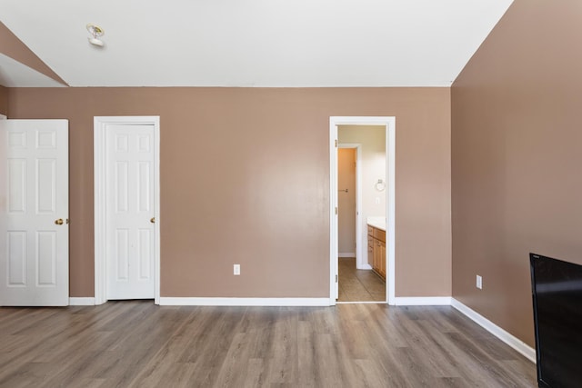 unfurnished bedroom featuring connected bathroom and light hardwood / wood-style flooring