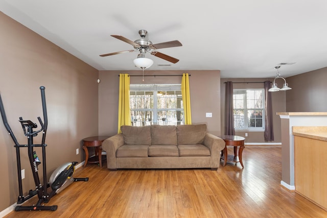 living room with ceiling fan, plenty of natural light, a fireplace, and light hardwood / wood-style floors