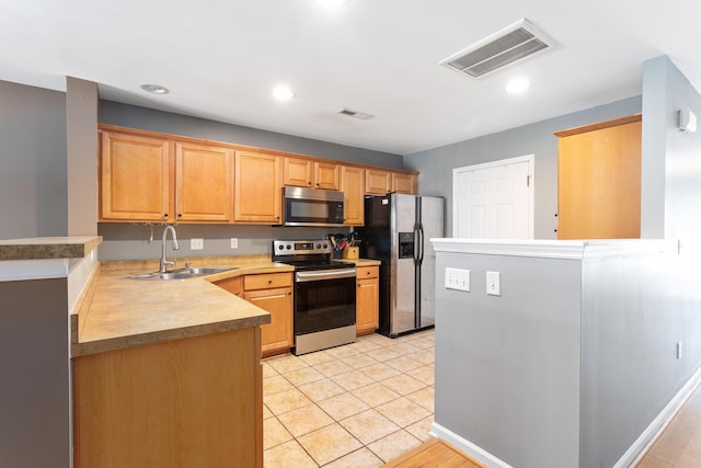 kitchen featuring light tile patterned flooring, appliances with stainless steel finishes, kitchen peninsula, and sink