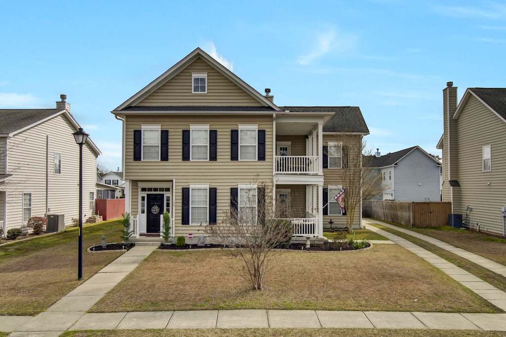 view of front of property with cooling unit, a balcony, and a front lawn