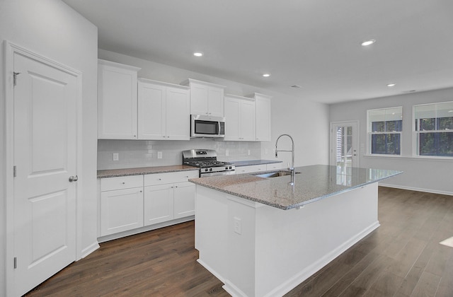 kitchen featuring stainless steel appliances, white cabinets, sink, and a kitchen island with sink