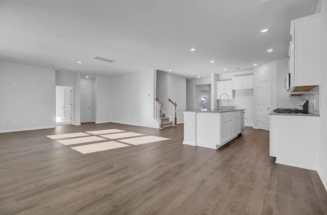 kitchen featuring white cabinetry, an island with sink, dark hardwood / wood-style floors, and stone countertops