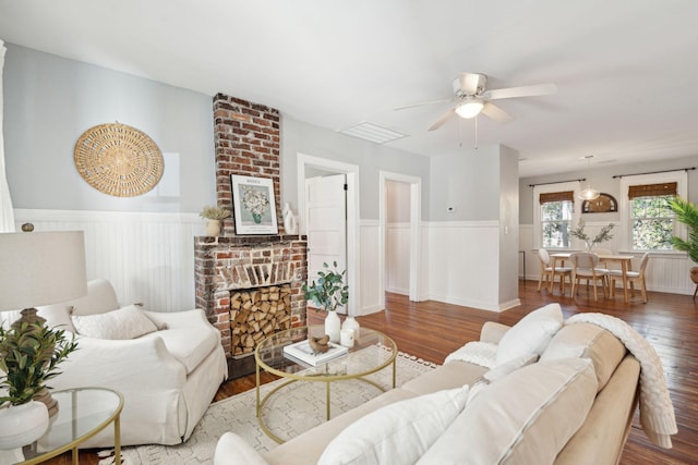 living room featuring dark wood-type flooring, ceiling fan, and a brick fireplace