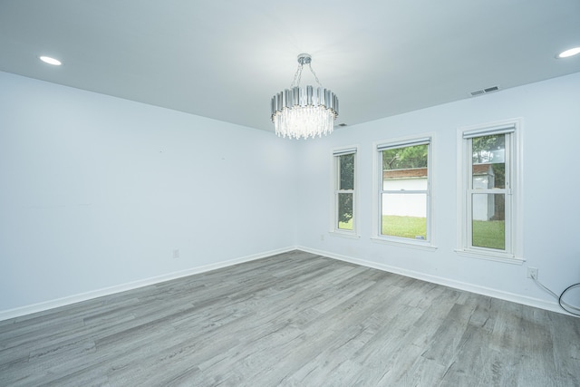 unfurnished room with a notable chandelier and light hardwood / wood-style floors