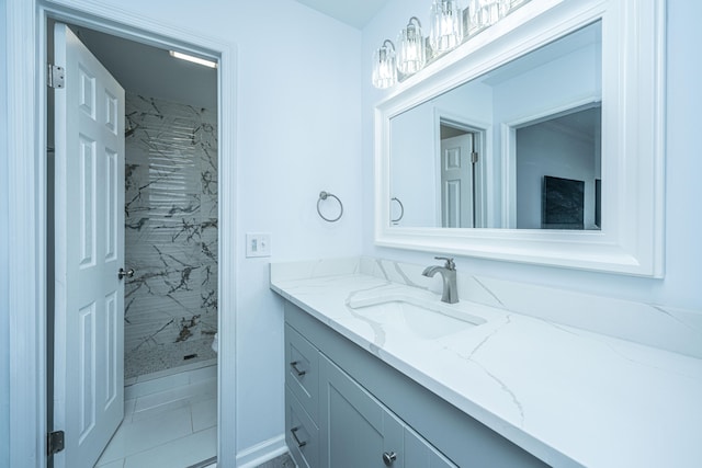 bathroom with tile patterned flooring, a tile shower, and vanity